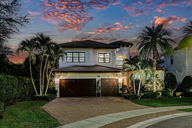 mediterranean / spanish-style house featuring a tiled roof, stucco siding, a front yard, a garage, and driveway