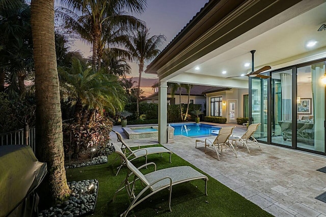 pool at dusk with grilling area, a yard, a patio area, and a fenced in pool