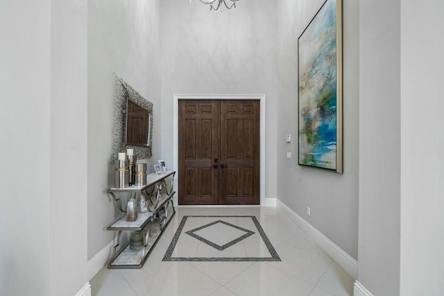 entrance foyer featuring a high ceiling, an inviting chandelier, baseboards, and tile patterned flooring
