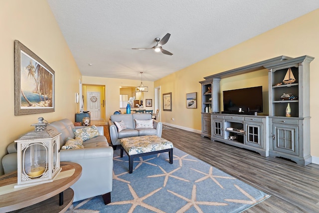living room featuring baseboards, a ceiling fan, wood finished floors, and a textured ceiling