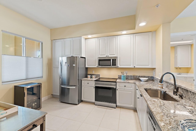 kitchen featuring a sink, stainless steel appliances, white cabinets, light stone countertops, and recessed lighting