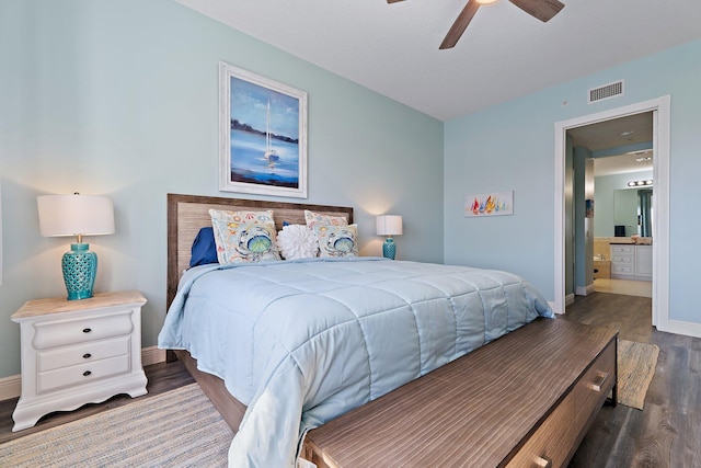 bedroom featuring wood finished floors, visible vents, a ceiling fan, ensuite bath, and baseboards