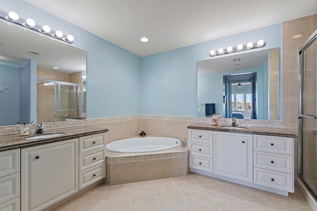 bathroom featuring tile patterned flooring, a sink, two vanities, a garden tub, and a stall shower