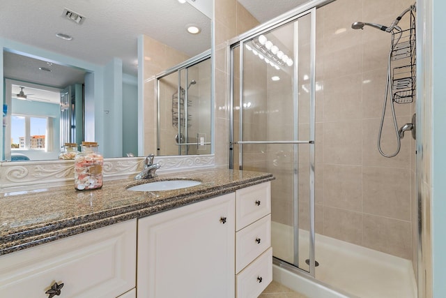 full bath with visible vents, vanity, a stall shower, and a ceiling fan