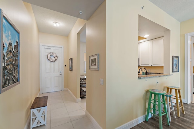 interior space featuring baseboards, a textured ceiling, and light tile patterned floors