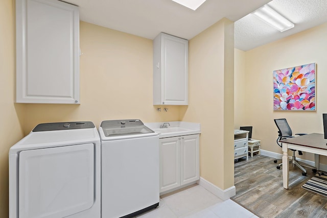 laundry room featuring a sink, light wood-style floors, cabinet space, baseboards, and independent washer and dryer