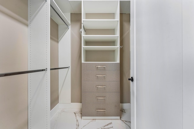 walk in closet featuring marble finish floors