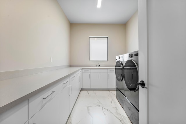 washroom with washing machine and dryer, light marble finish floors, and cabinet space