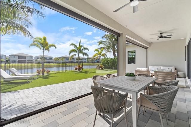 view of patio / terrace with ceiling fan, a water view, outdoor dining space, and a residential view