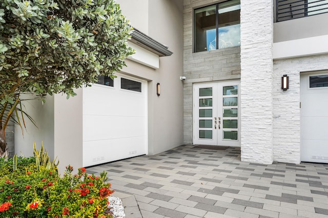 property entrance featuring french doors, stone siding, and stucco siding