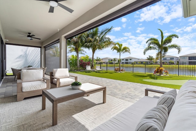 view of patio / terrace featuring a ceiling fan, a water view, outdoor lounge area, and a putting green