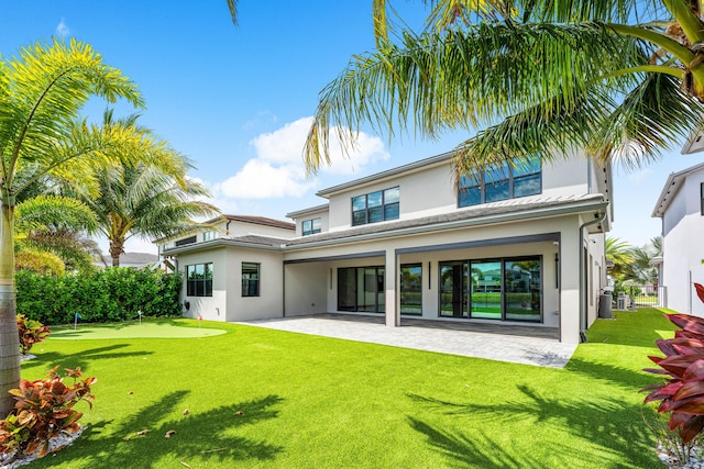 back of house featuring a putting green, a patio area, stucco siding, and a lawn