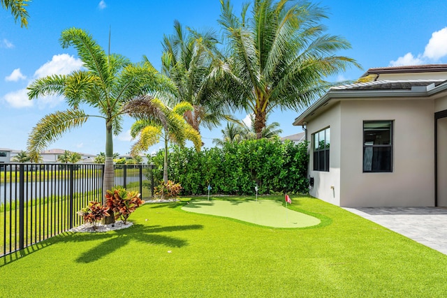 view of yard with an area to practice putting, a water view, and a patio