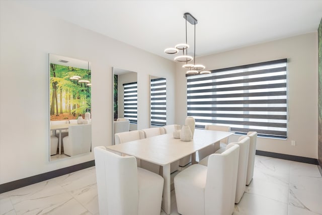 dining space with light marble finish flooring, baseboards, and healthy amount of natural light