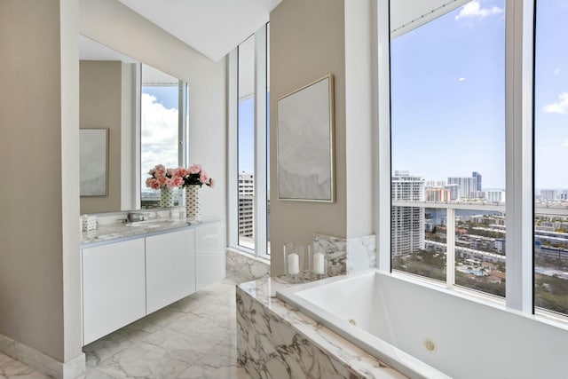 full bath featuring a city view, a jetted tub, vanity, and marble finish floor