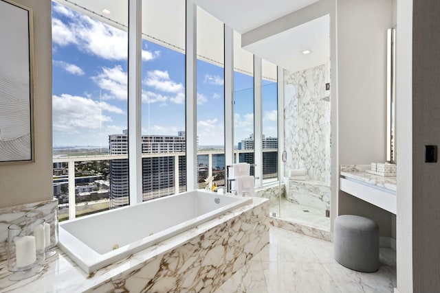 bathroom featuring a garden tub, vanity, a marble finish shower, marble finish floor, and a city view
