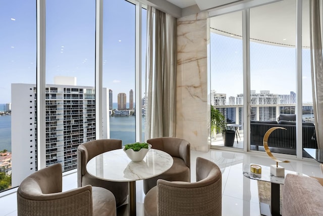 dining area with a city view, tile patterned floors, a wall of windows, and a water view
