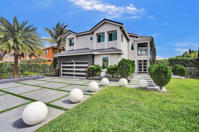 contemporary home with stucco siding, fence, a front lawn, and a garage