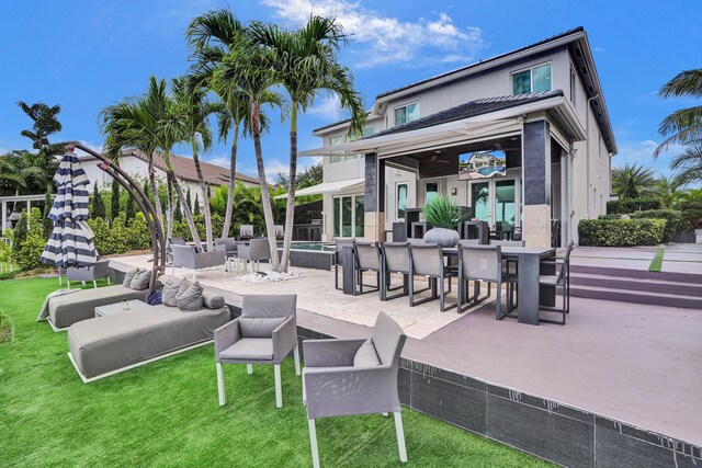back of property with an outdoor living space, outdoor dining area, a yard, a patio, and stucco siding