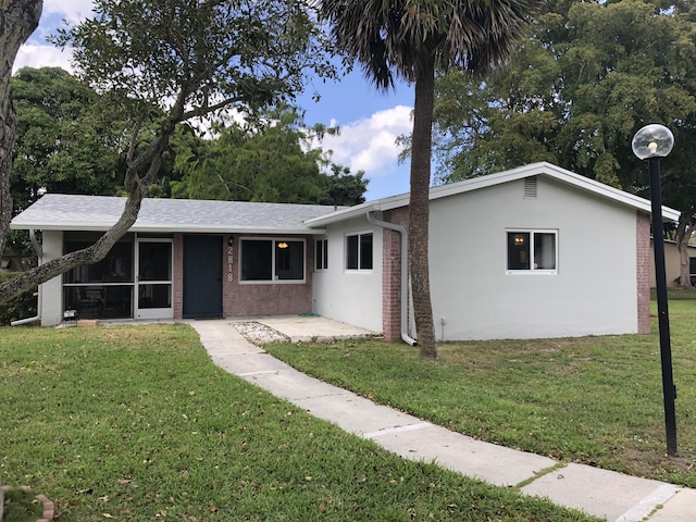 single story home with a front lawn, a sunroom, and stucco siding