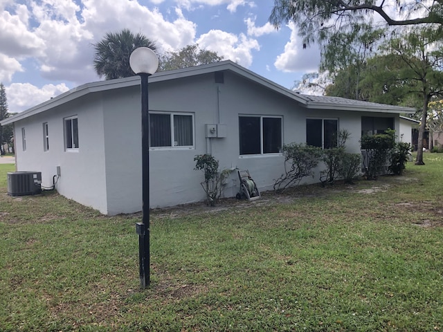 back of house featuring stucco siding, central air condition unit, and a yard