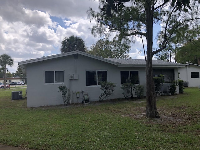 back of property featuring stucco siding, a yard, and central AC unit