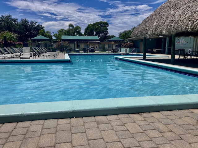 community pool with a patio area, fence, and a gazebo