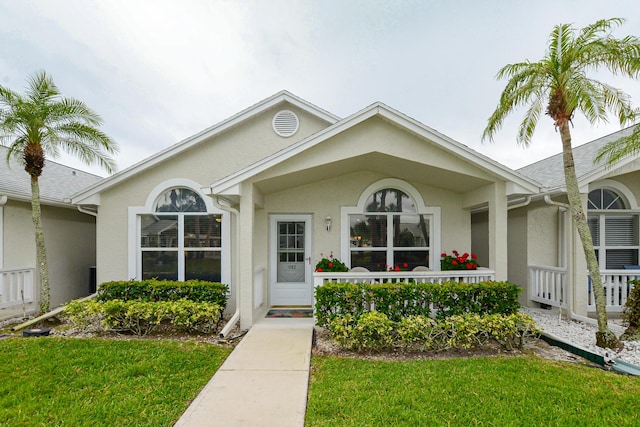 property entrance with a yard, covered porch, and stucco siding