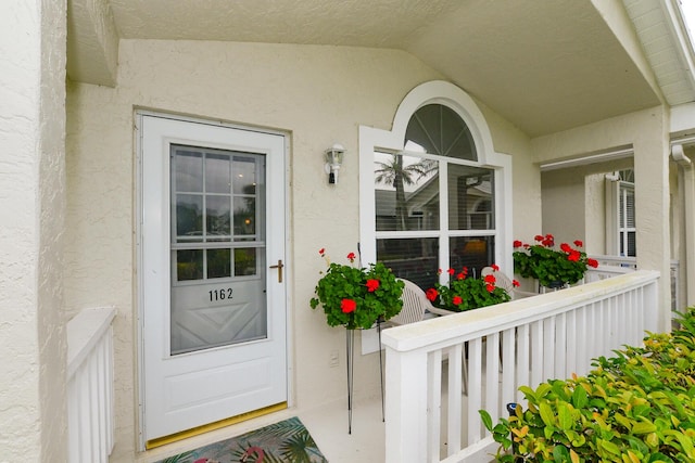 view of exterior entry featuring covered porch and stucco siding