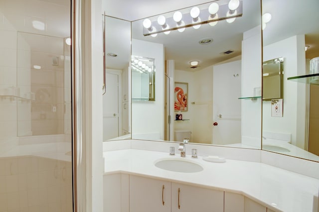 bathroom with a shower with shower door, vanity, visible vents, and toilet