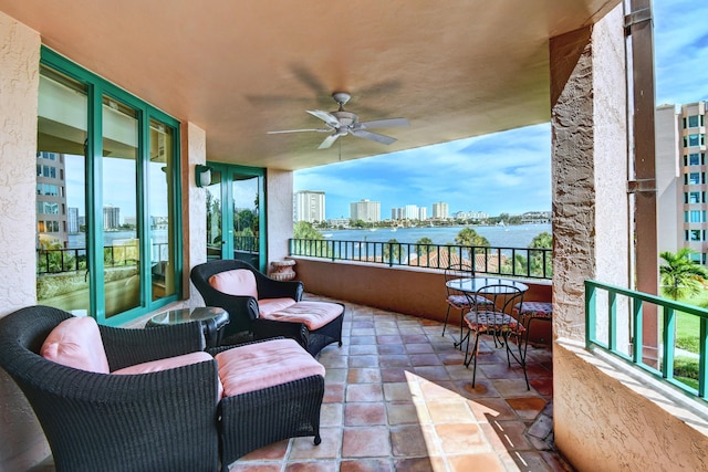balcony featuring a water view, a city view, and a ceiling fan