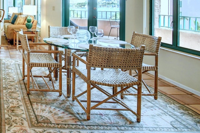 tiled dining area featuring baseboards and a healthy amount of sunlight