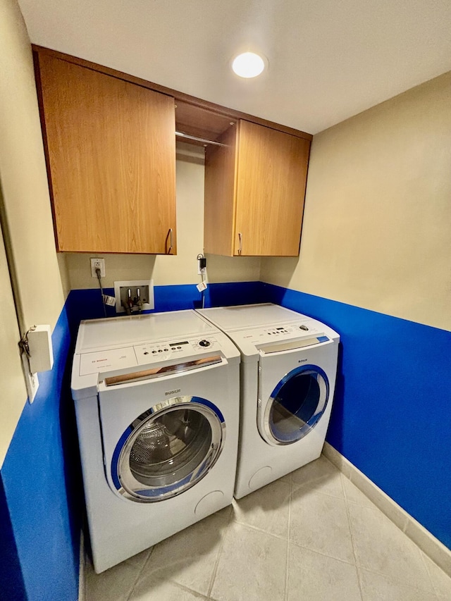 washroom with cabinet space, independent washer and dryer, tile patterned floors, and baseboards
