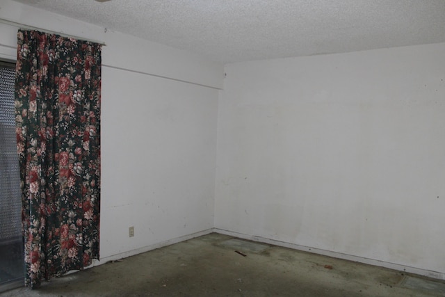 empty room featuring a textured ceiling and concrete floors