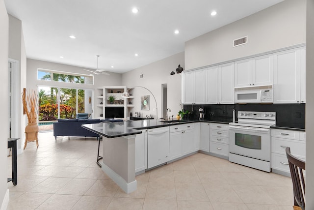 19699 Dinner Key Dr, Boca Raton, FL 33498 - kitchen with dark countertops, visible vents, white appliances, a peninsula, and tasteful backsplash