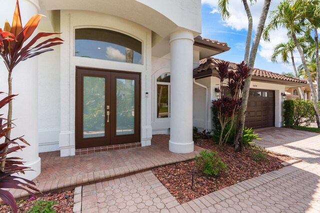 19699 Dinner Key Dr, Boca Raton, FL 33498 - property entrance with an attached garage, french doors, stucco siding, and driveway