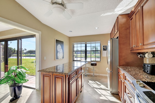 8326 Mooring Cir, Boynton Beach, FL 33472 - kitchen featuring appliances with stainless steel finishes, brown cabinets, light tile patterned floors, dark stone countertops, and baseboards