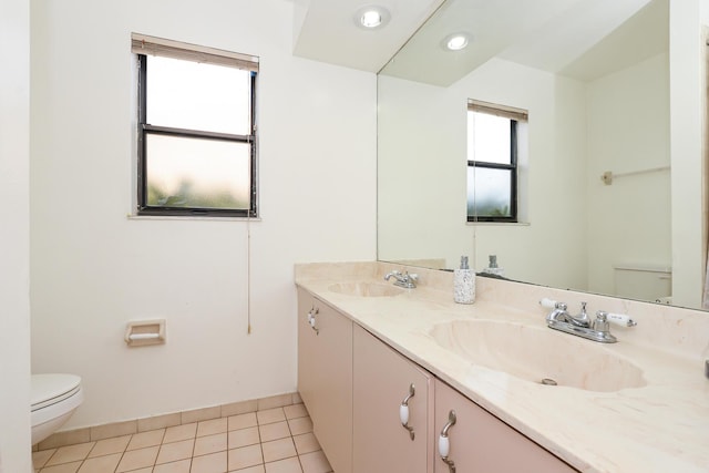 bathroom with toilet, tile patterned floors, double vanity, and a sink