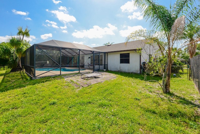 rear view of property featuring a yard, stucco siding, a patio, fence, and a lanai