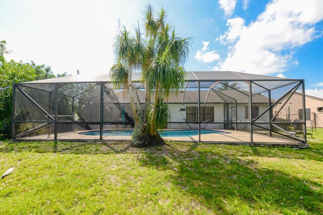 back of property featuring an outdoor pool, a patio, a yard, and glass enclosure