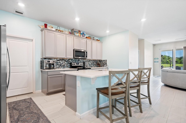 1908 Harding St, Lake Worth, FL 33460 - kitchen with stainless steel appliances, backsplash, open floor plan, a kitchen breakfast bar, and an island with sink