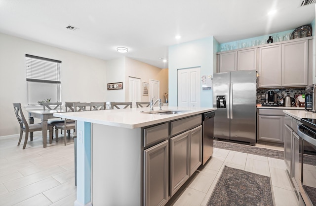 1908 Harding St, Lake Worth, FL 33460 - kitchen featuring stainless steel appliances, gray cabinetry, light countertops, backsplash, and a kitchen island with sink