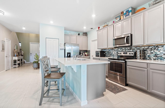 1908 Harding St, Lake Worth, FL 33460 - kitchen featuring stainless steel appliances, backsplash, a kitchen bar, light countertops, and a center island with sink
