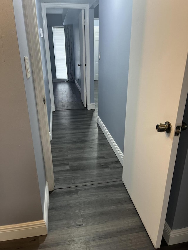 corridor featuring baseboards and dark wood finished floors
