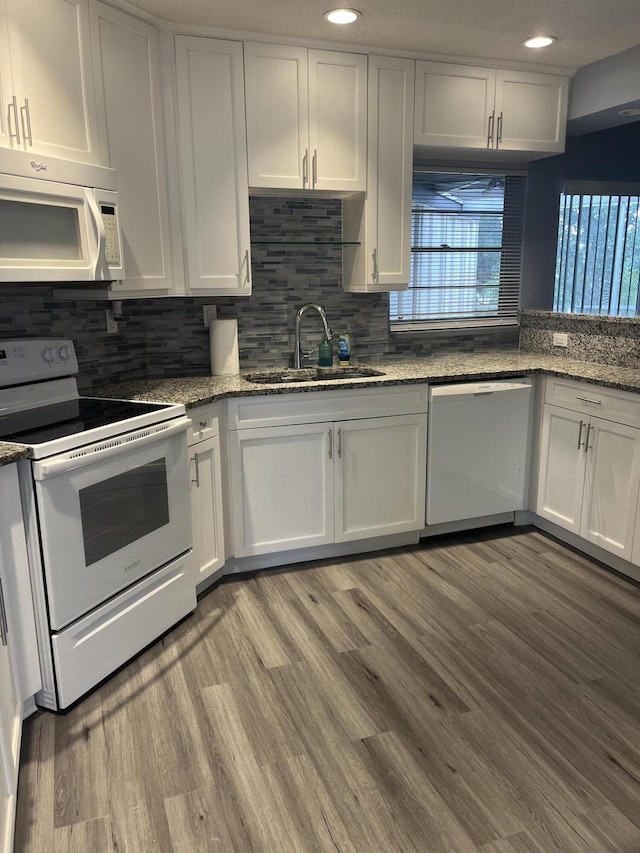 kitchen featuring white cabinetry, a sink, white appliances, and plenty of natural light