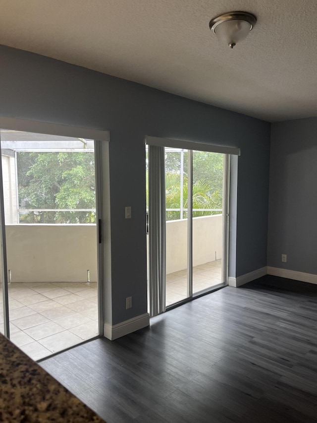 spare room with a wealth of natural light, a textured ceiling, baseboards, and wood finished floors