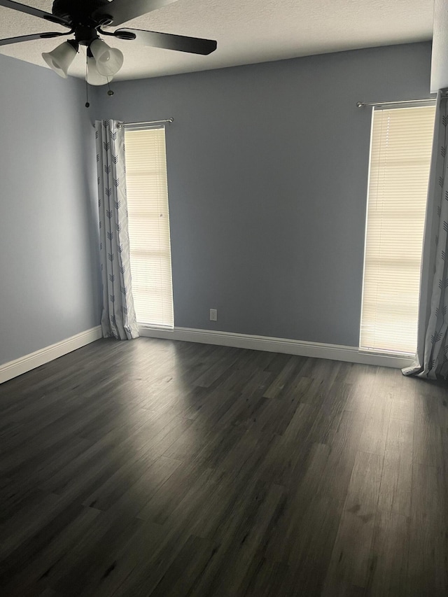 spare room with dark wood-style flooring, baseboards, and a ceiling fan