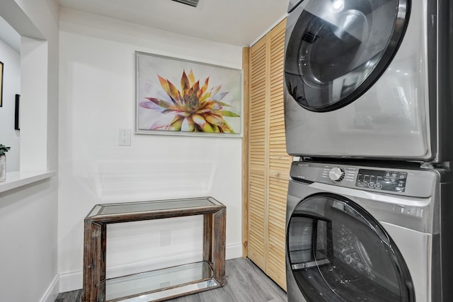 1013 Green Pine Blvd Unit A1, West Palm Beach, FL 33409 - clothes washing area featuring stacked washer and clothes dryer, light wood-style floors, and baseboards