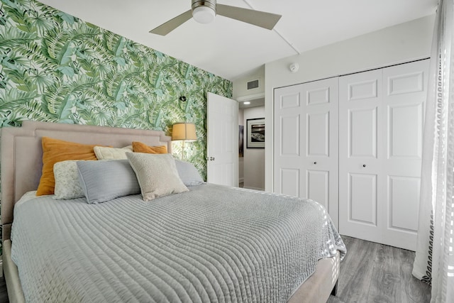 1013 Green Pine Blvd Unit A1, West Palm Beach, FL 33409 - bedroom featuring wallpapered walls, an accent wall, a closet, wood finished floors, and ceiling fan