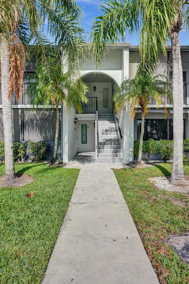 1013 Green Pine Blvd Unit A1, West Palm Beach, FL 33409 - entrance to property with stucco siding, a lawn, concrete driveway, and covered porch